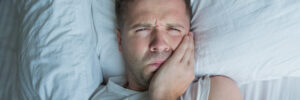 Man holding toothache in bed