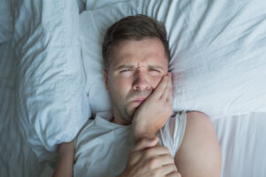 Man holding toothache in bed