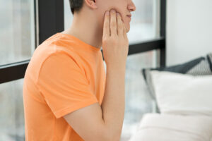 A man with toothache holding side of face