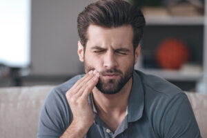 Frustrated young man touching toothache